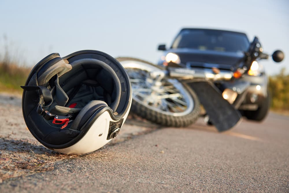 helmet and motorcycle lying on road in front of car