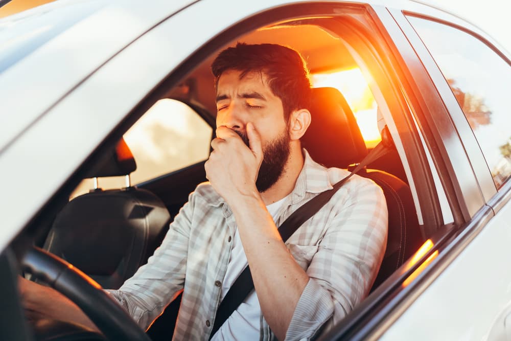 male driver yawning and closing eyes while operating vehicle; drowsy driving accidents
